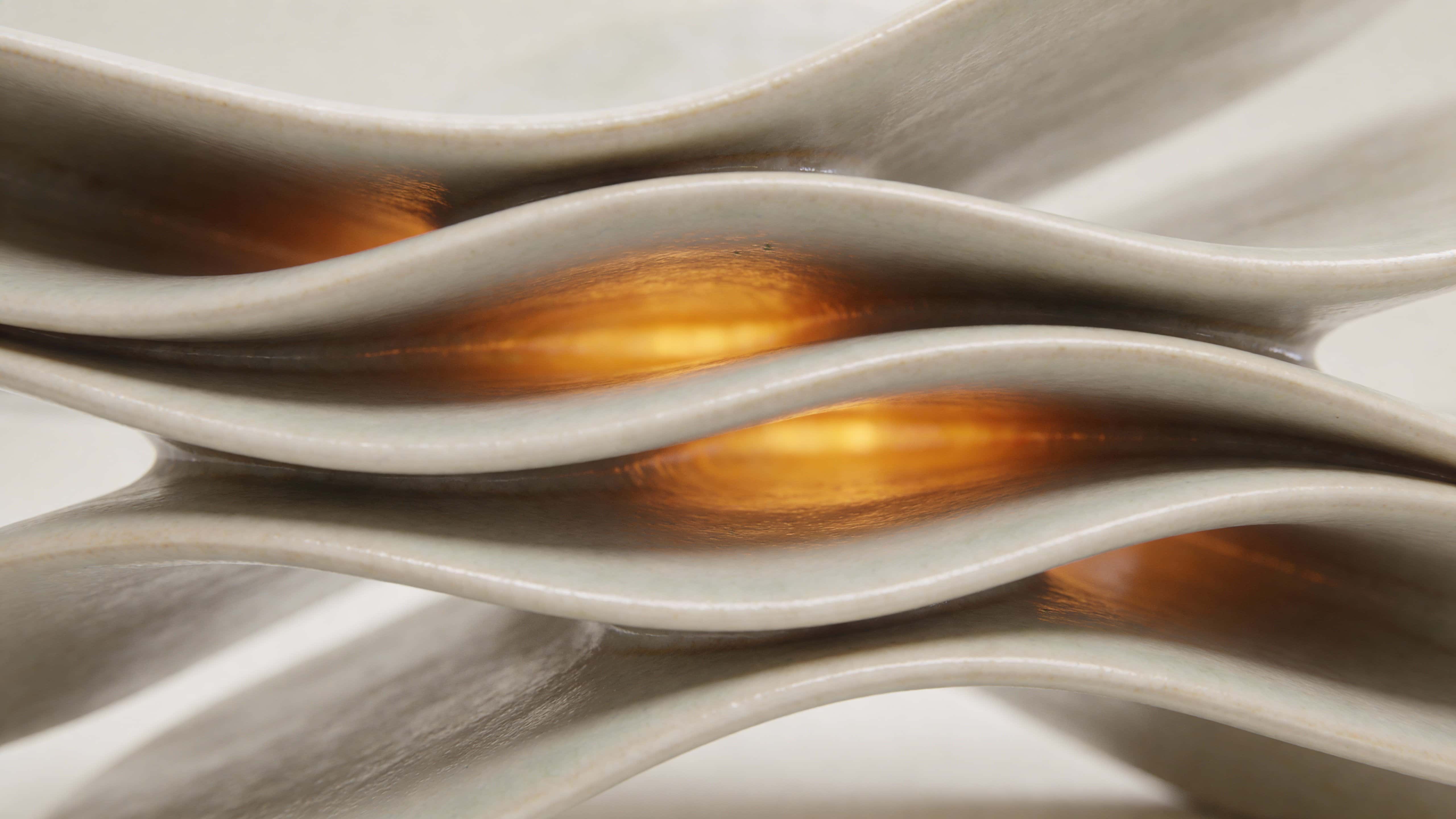 A premium CGI-rendered abstract ceramic sculpture of overlapping folded surfaces with an inner amber glow illuminating organic wave-like layers, centered and framed within a 16:9 minimal neutral background.