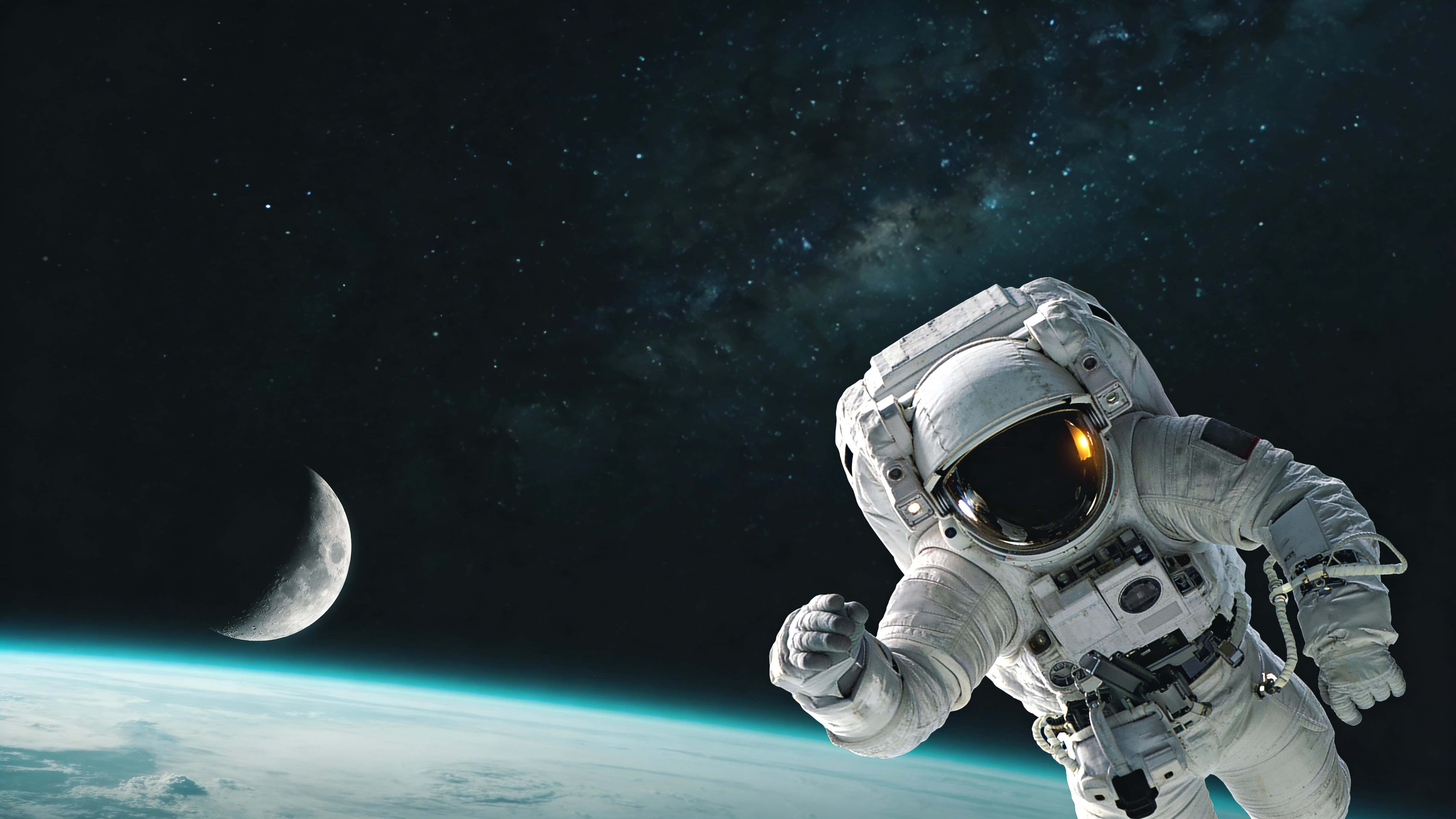A dramatic editorial-style space photograph of a lone astronaut floating against a vast starfield and distant Earth, composed for a 16:9 wallpaper or poster use.