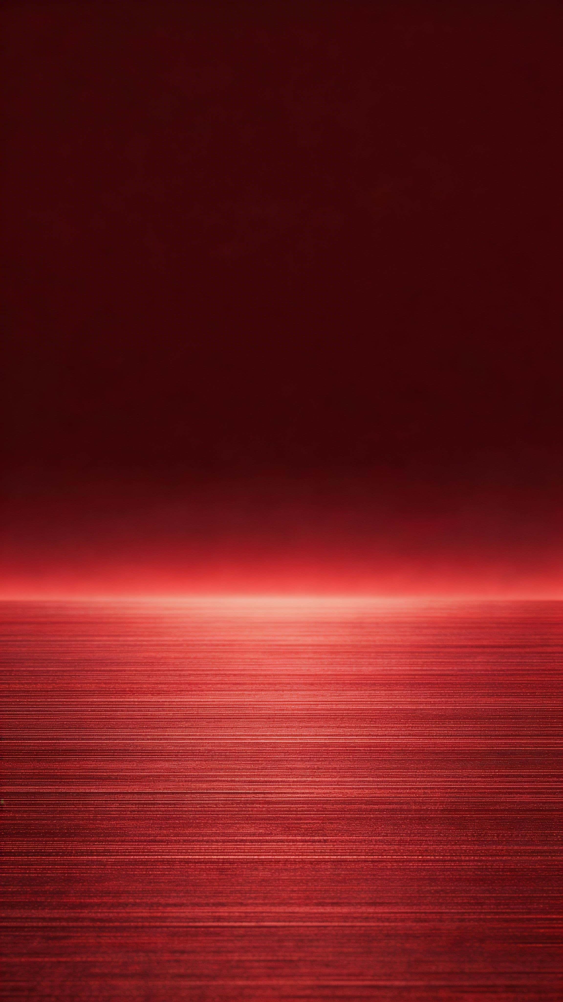 Vertical 9:16 studio product photograph of subtle brushed red metal with fine grain, featuring a soft low-to-mid highlight band that fades into a clean, darker top for negative space.