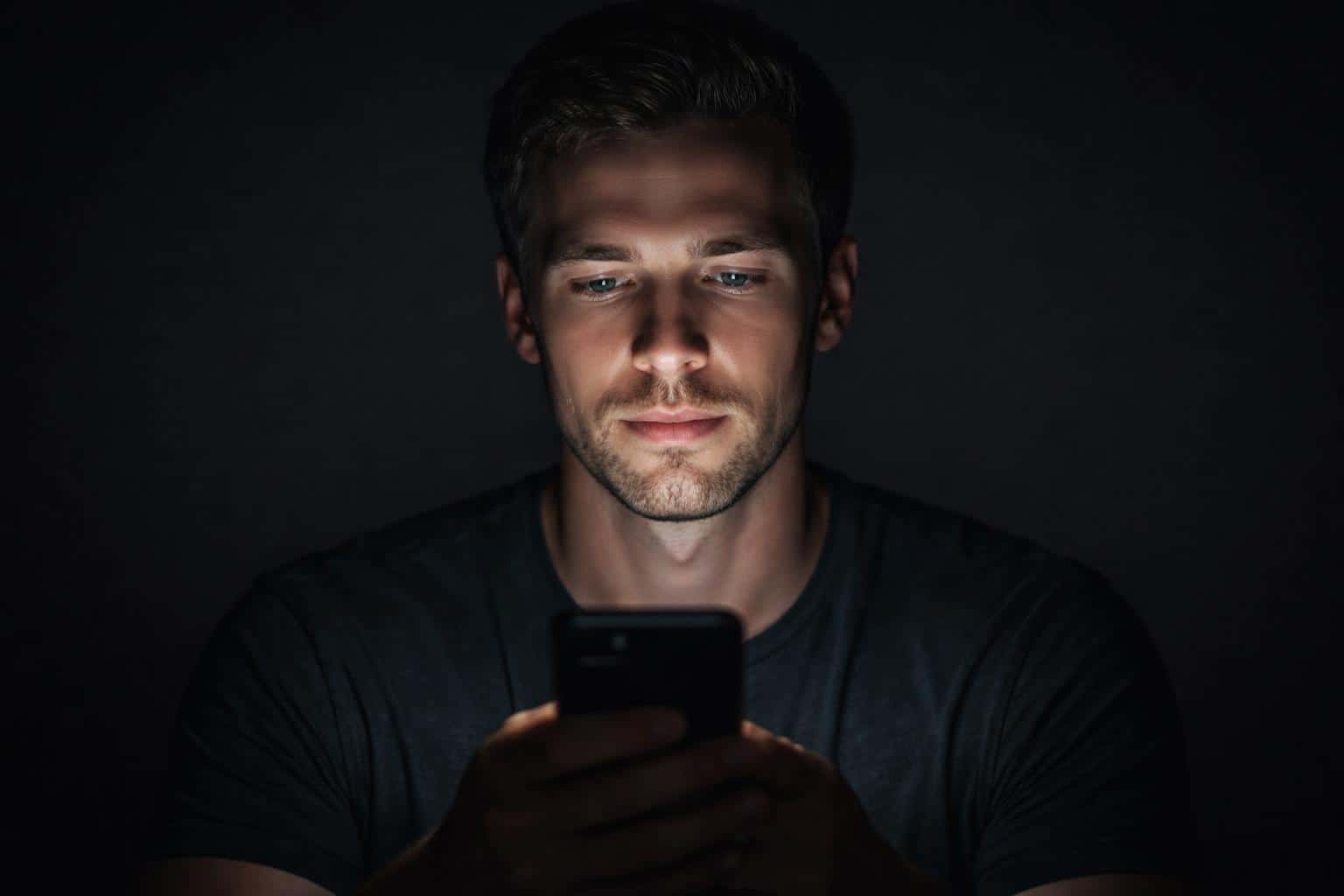 Casual close-up portrait lit only by a phone screen, composed in 3:2 aspect ratio for intimate social-post or editorial use with a low-key, personal mood.