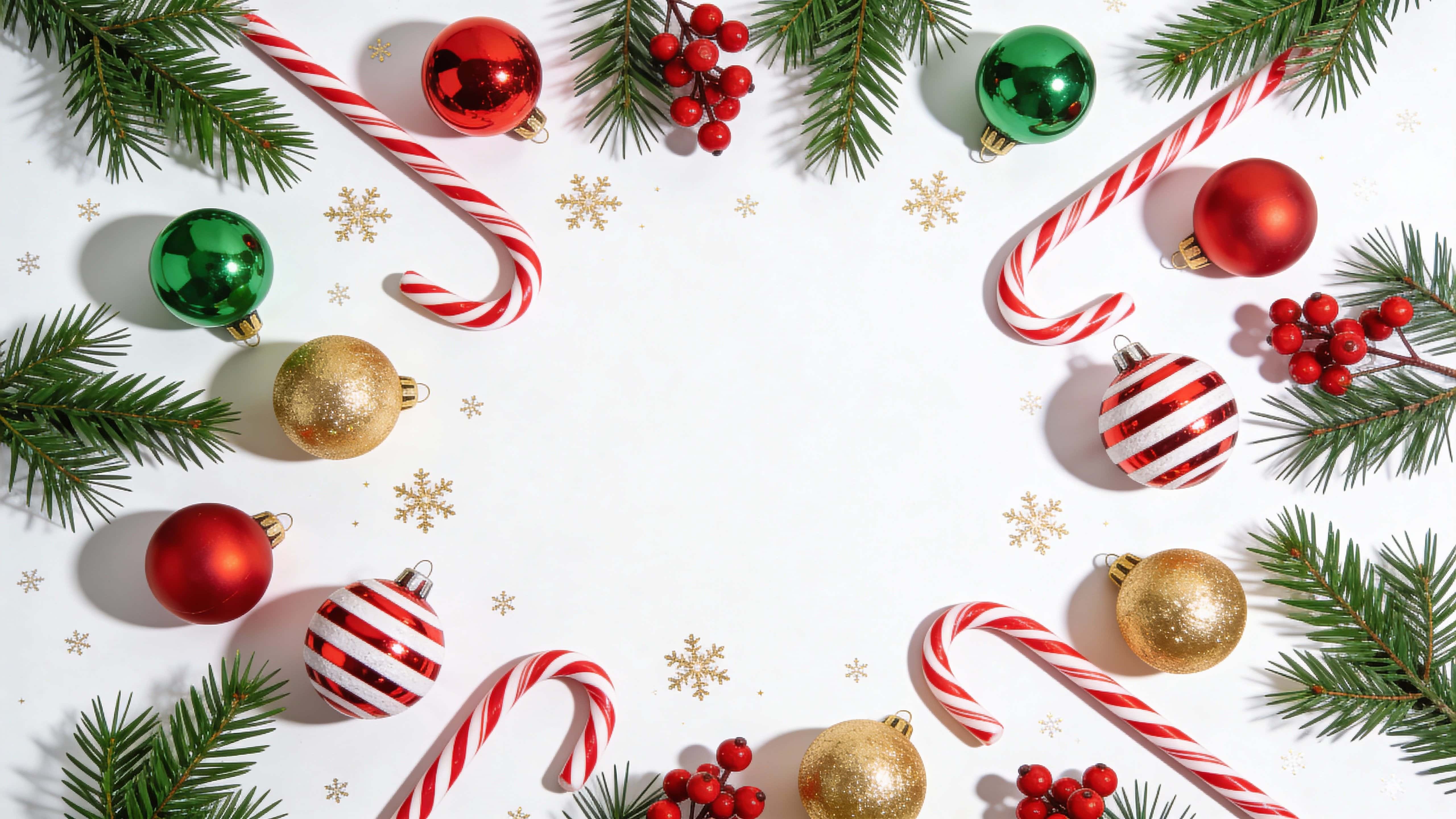 Top-down 16:9 Christmas flat lay border on a white background showing fresh pine branches, diagonal red-and-white candy canes, red, green and gold baubles, red berries and gold snowflake confetti.