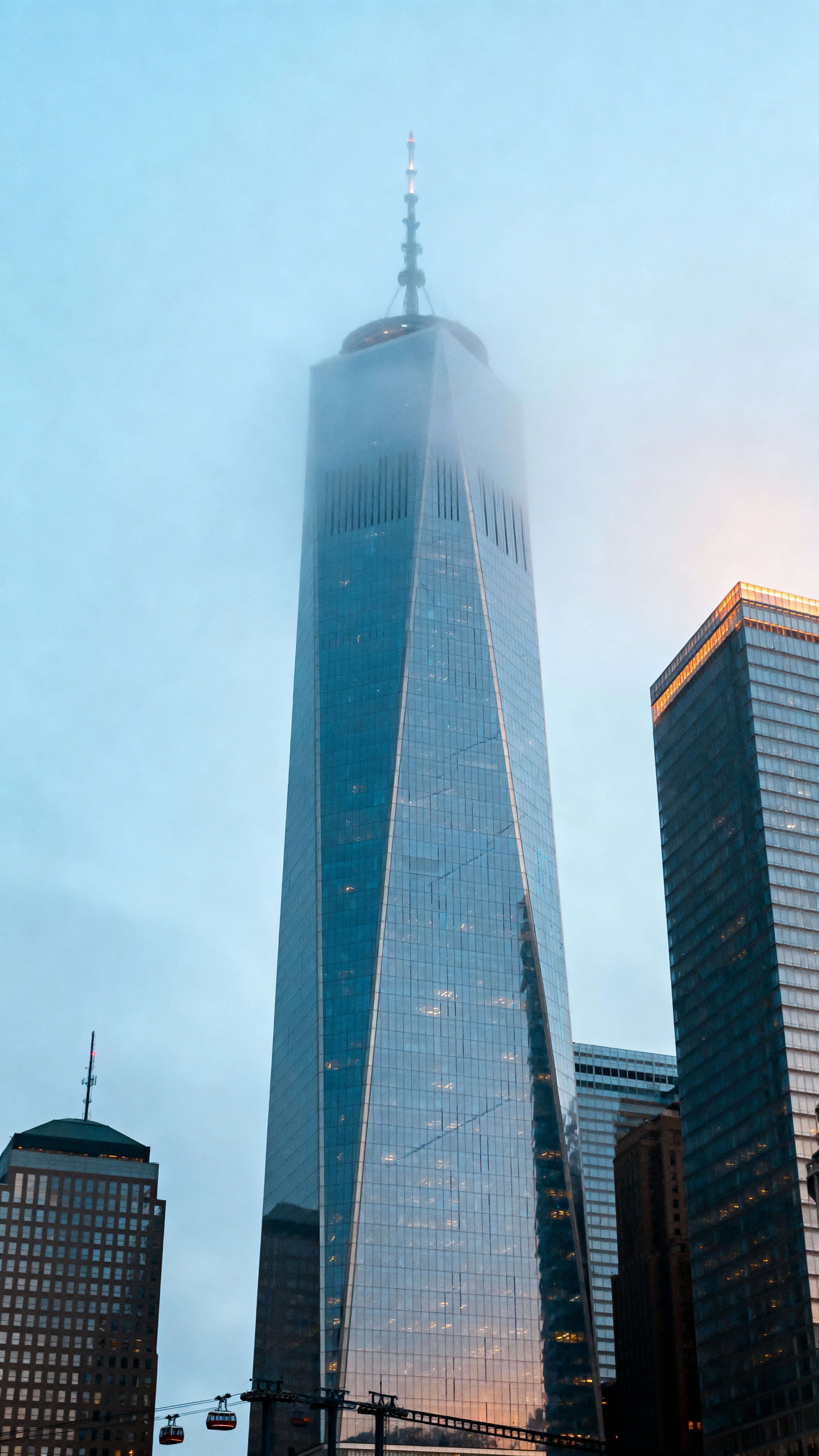 A vertical cinematic view of chrome skyscrapers rising through cool mist in a 9:16 frame, emphasizing reflective surfaces, layered depth, and a quiet futuristic mood for editorial or wallpaper use.