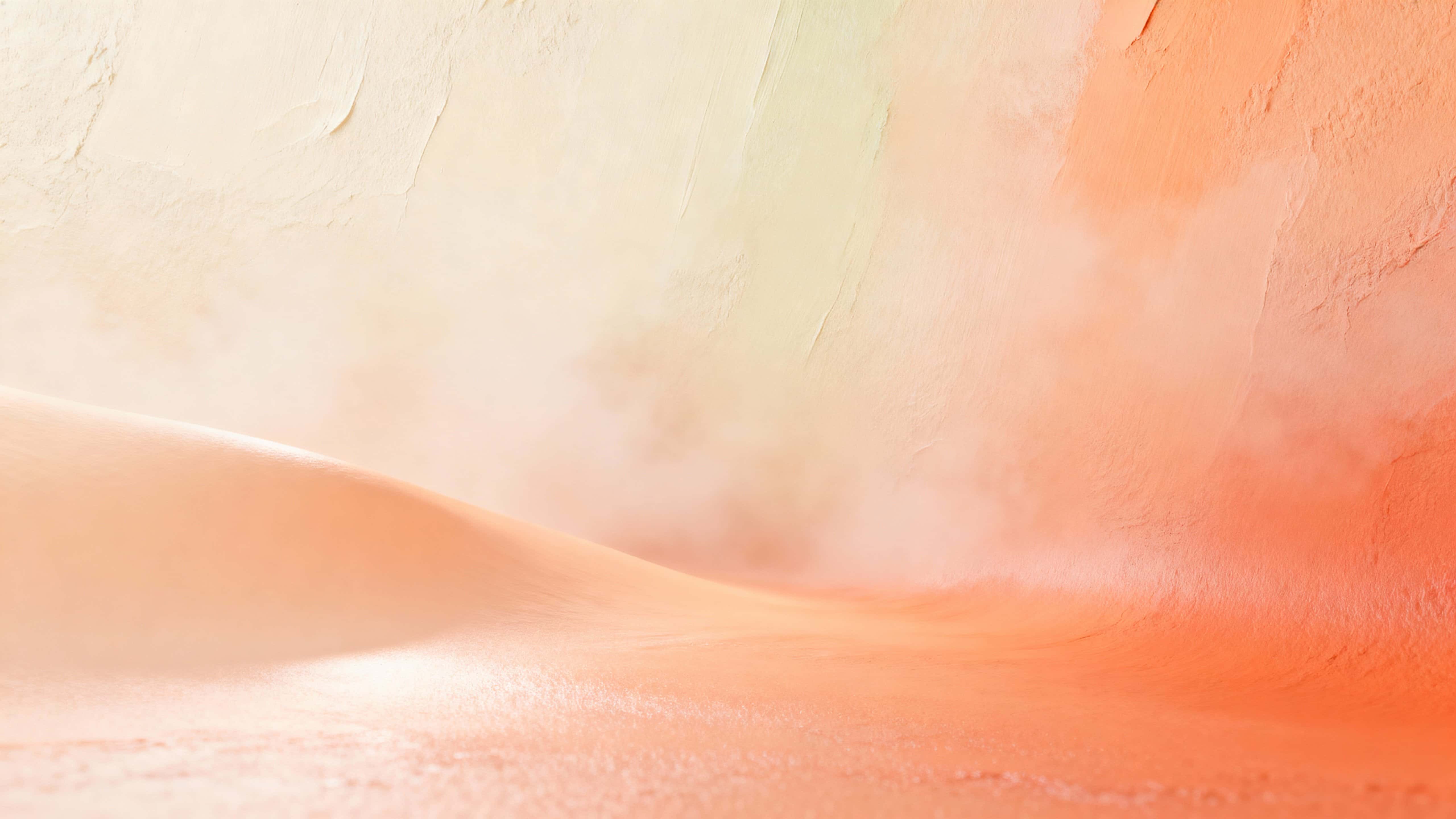 An ultra-soft 16:9 color field of blended pale coral, melon, peach, and cream forming a misty diagonal gradient from deeper lower-right coral-melon to pale upper-left peach-cream.