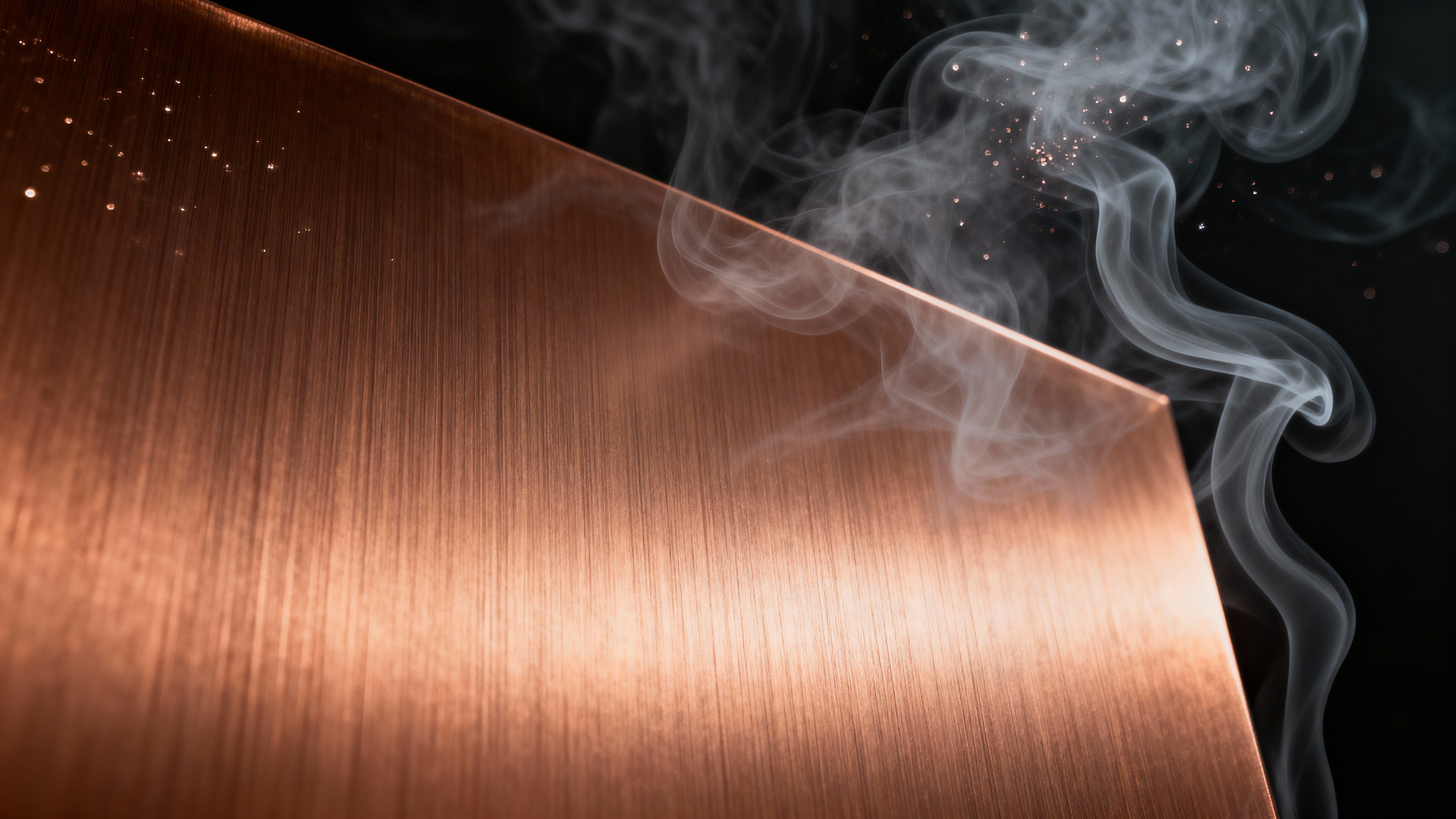 A brushed copper plane with fine directional grain sits front-and-center against translucent gray smoke wisps and deep charcoal tones, with pale metallic speckles and soft glancing light for an editorial background.