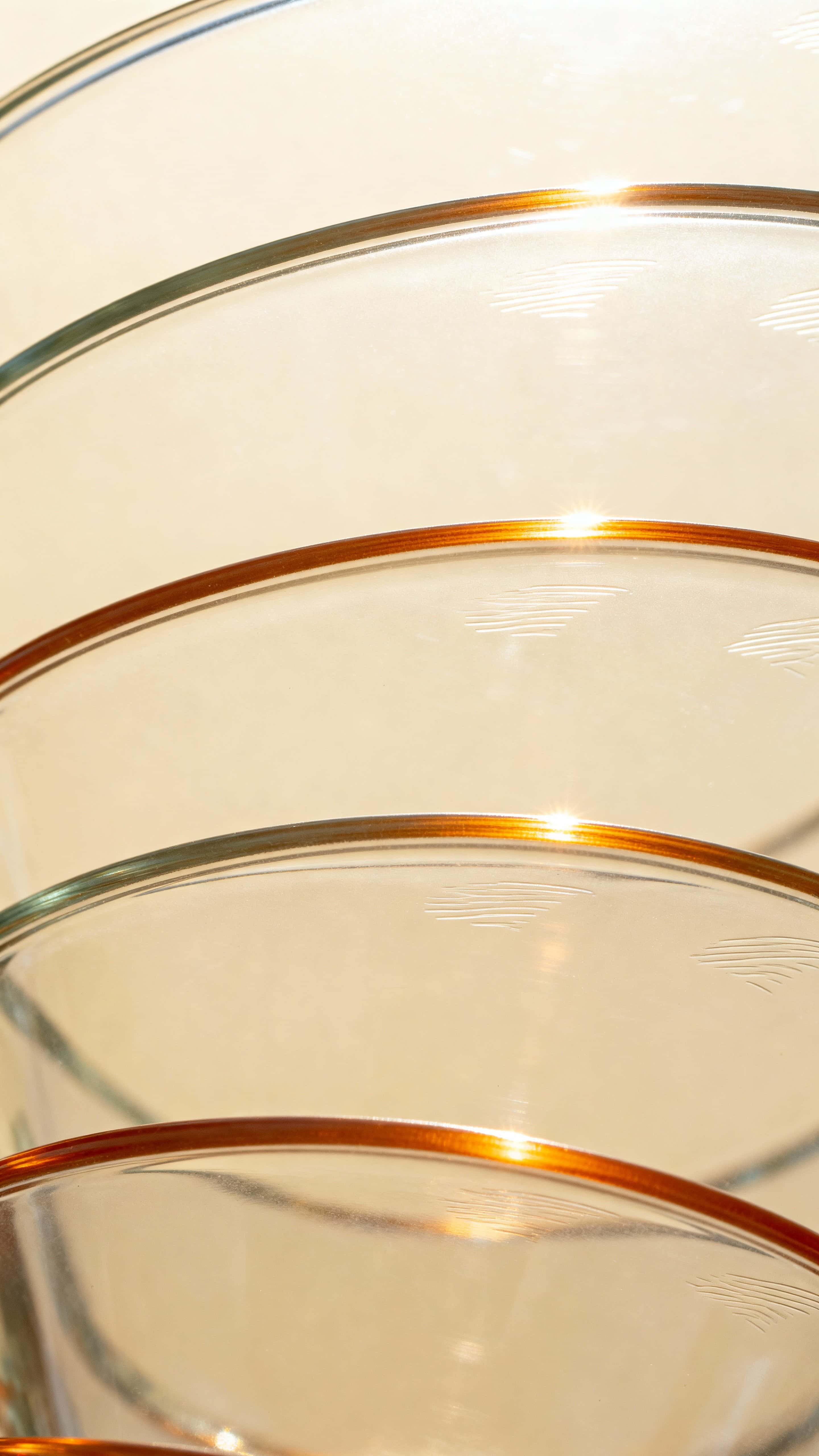 A cinematic macro study of curved transparent glass surfaces reflecting warm sunlight with smooth edges and bright minimalist framing, captured as an elegant vertical 9:16 crop for portrait display.