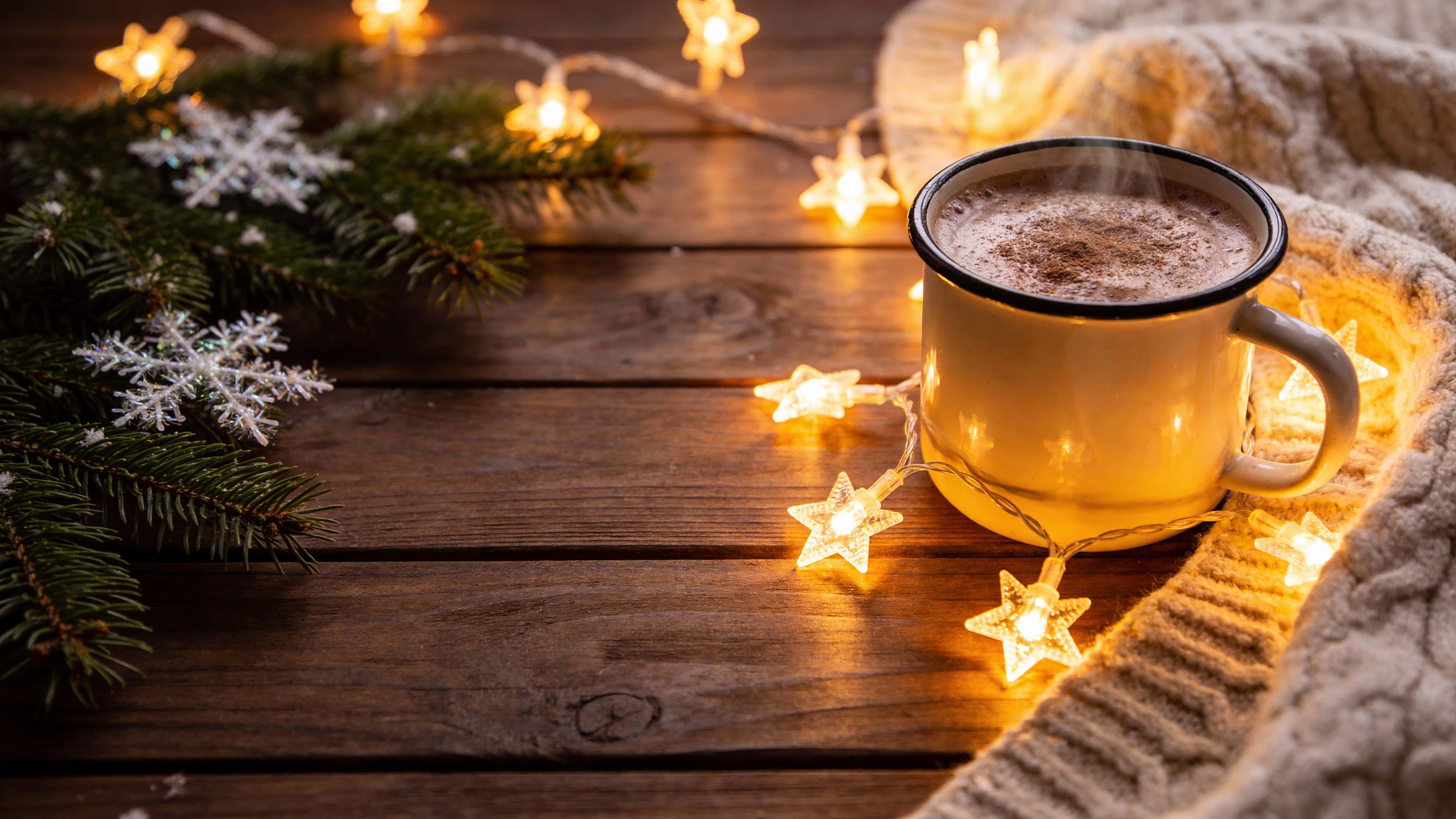 A 16:9 view of extra-warm fairy lights draped along a slightly darker wooden mantel and wall, casting a soft golden glow that creates a cozy winter mood.
