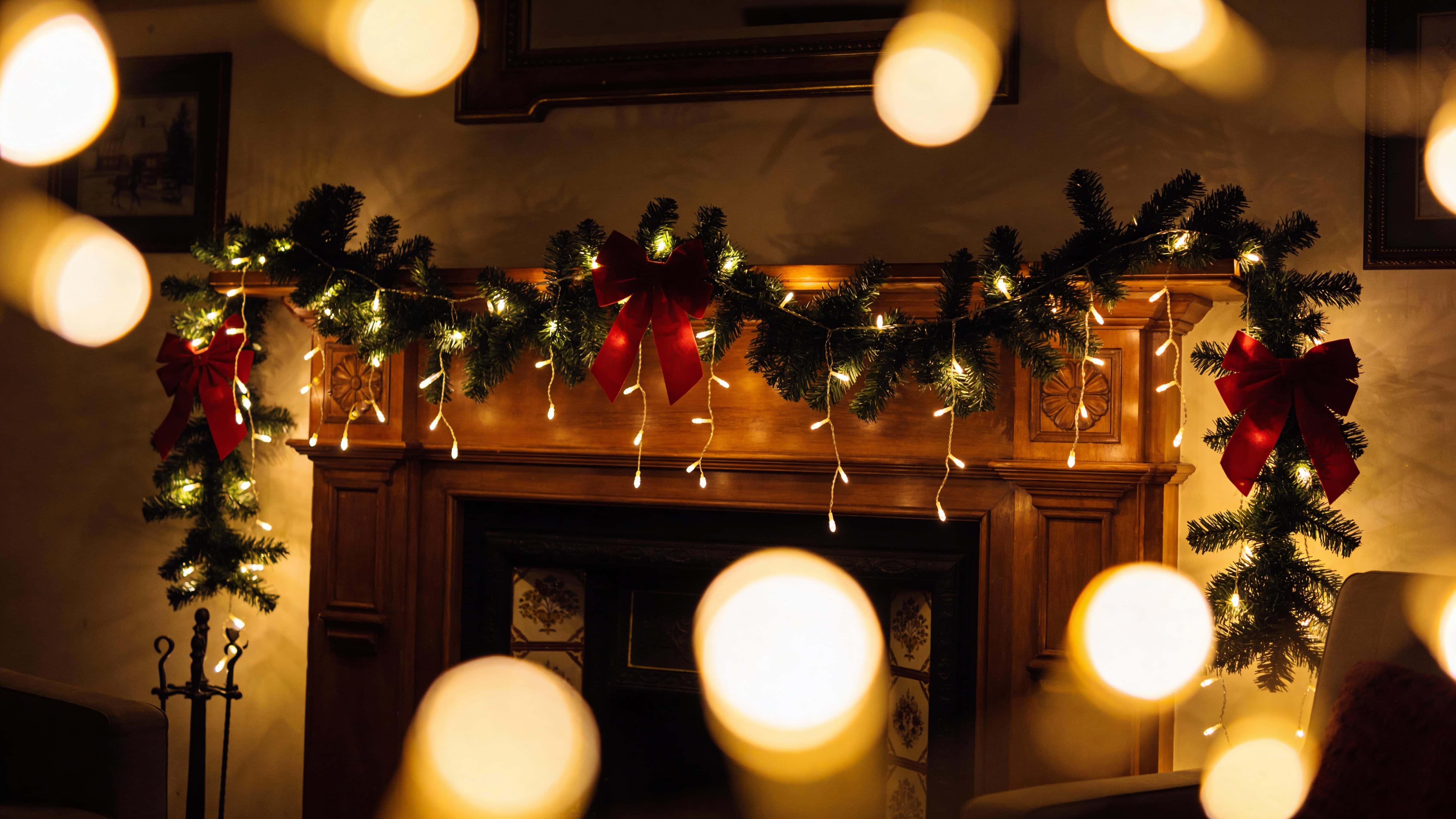 House facade and nearby trees framed in a 16:9 wide view at dusk, bathed in slightly dark ambient light and warm glowing fairy lights for a cozy evening holiday mood.