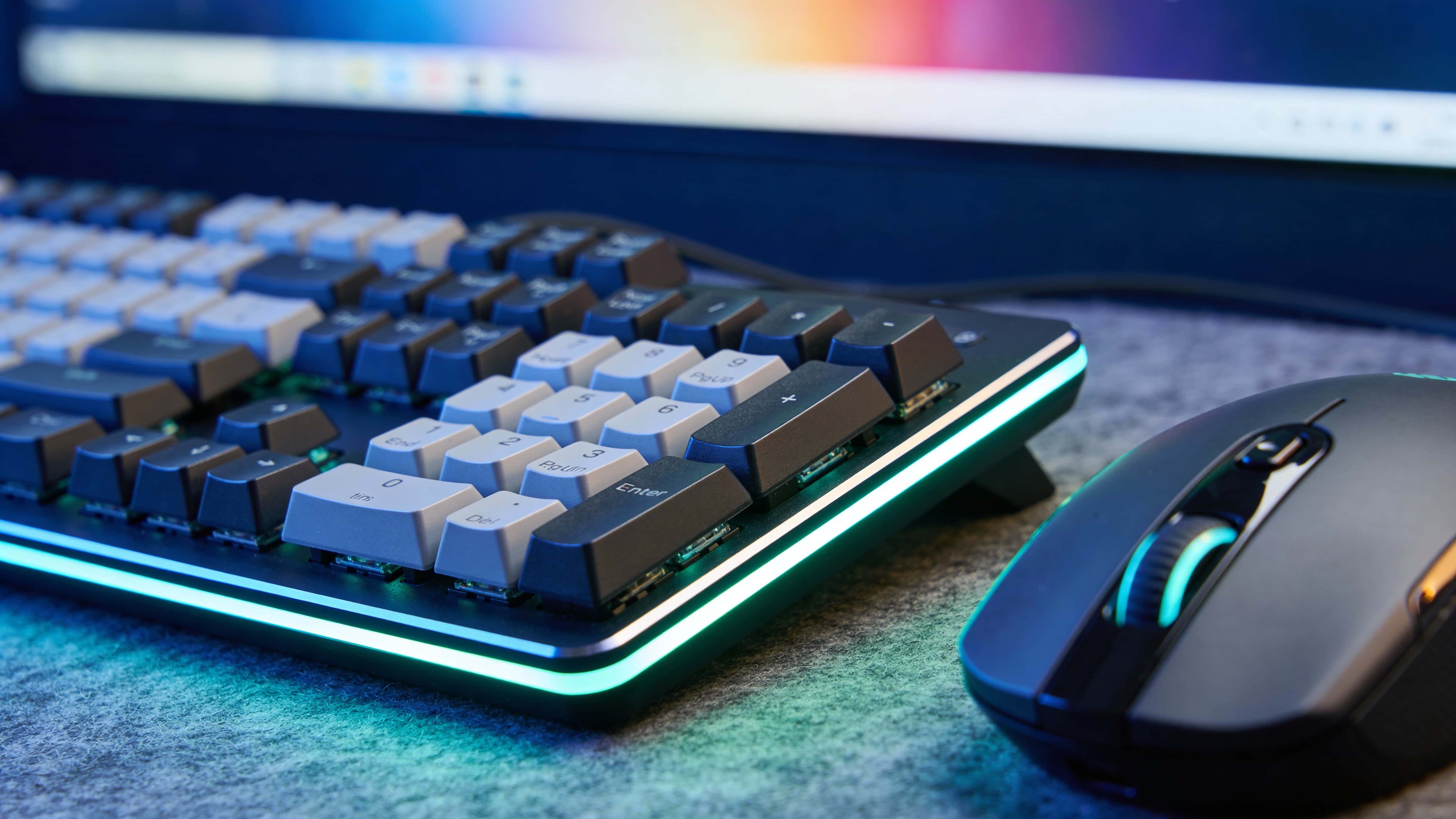 Neon-lit keyboard and mouse product photography arranged as a 16:9 wallpaper hero, with moody contrast, crisp reflections, and a sleek tech aesthetic.