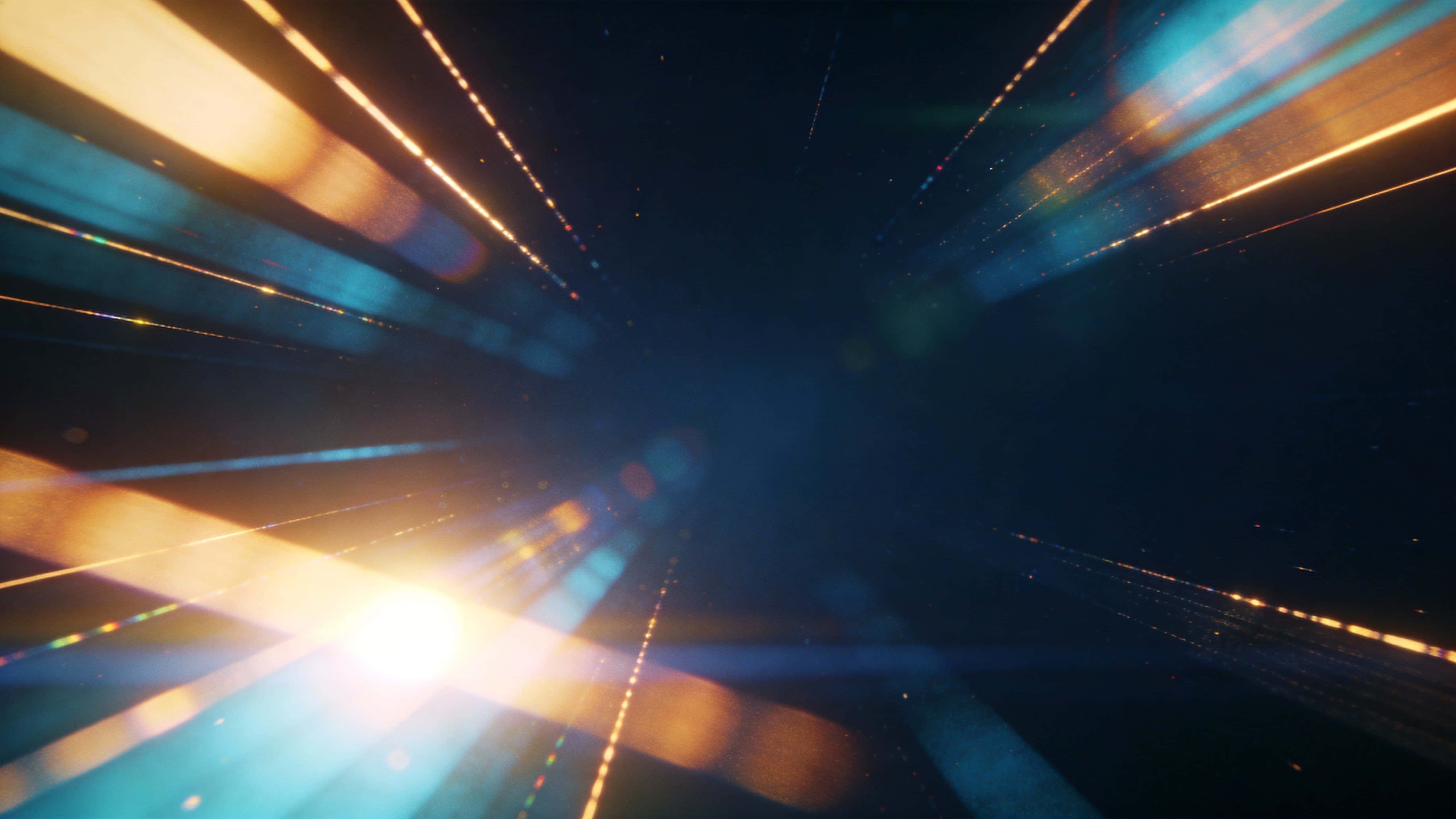 Cinematic 16:9 digital background of warm light leaks and soft lens flares, rendered as an abstract photographic texture for wallpaper or cinematic poster use with gentle film grain.