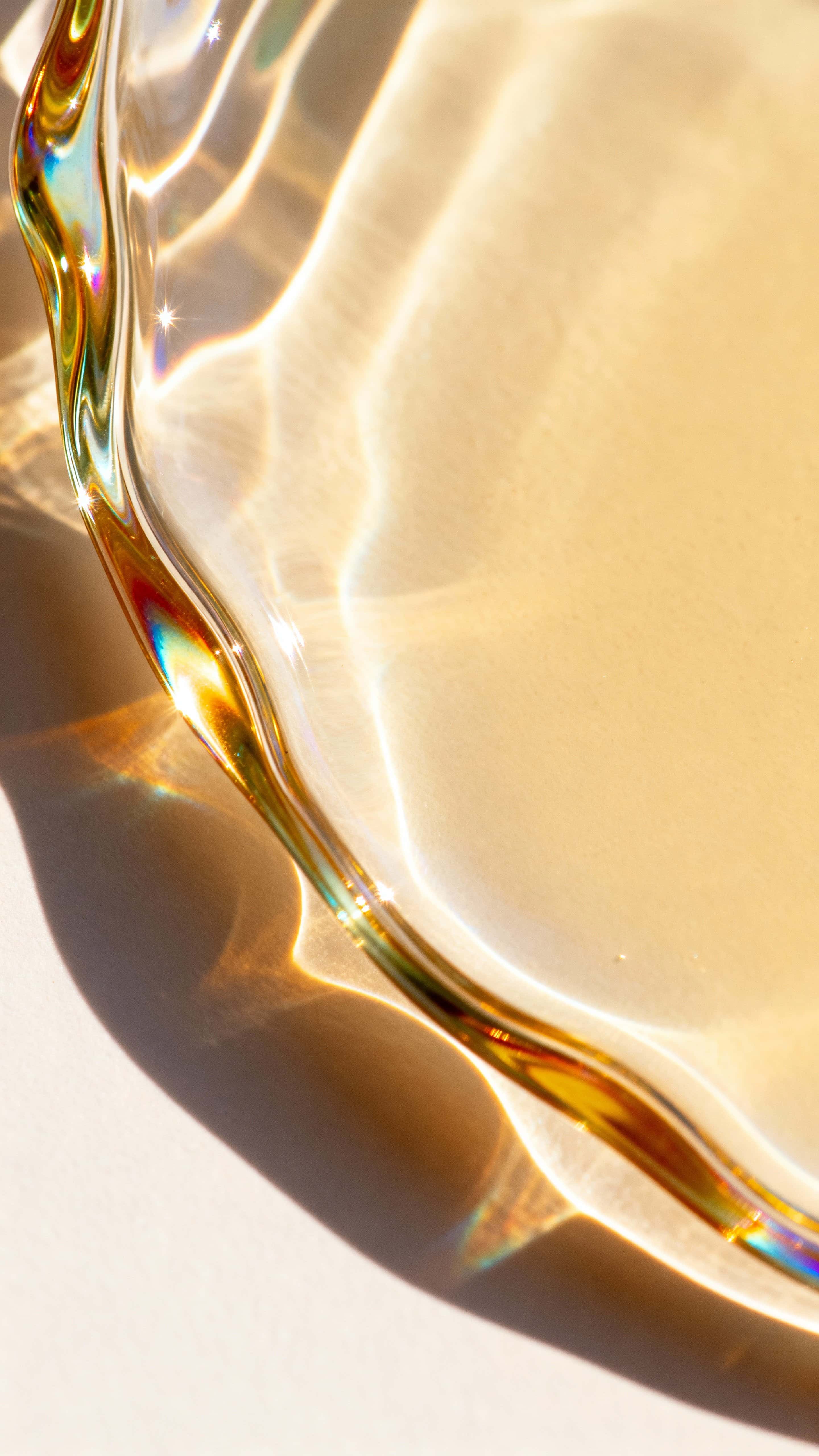 A 9:16 vertical wallpaper of liquid-glass abstract forms with iridescent highlights, subtle gradients and cinematic depth, showing natural reflection and refraction in a minimalist composition centered for mobile display.