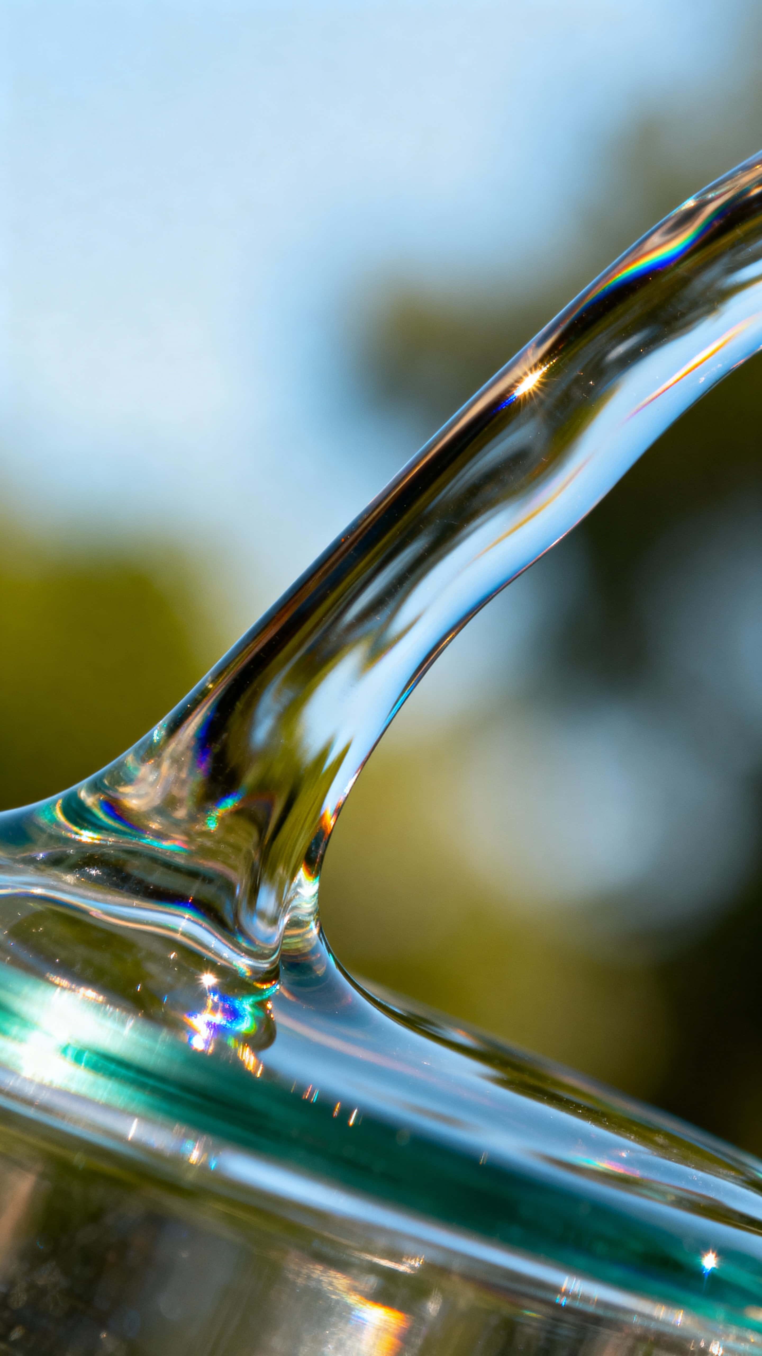 A 9:16 vertical wallpaper of liquid-glass abstract forms with iridescent highlights, subtle gradients and cinematic depth, showing natural reflection and refraction in a minimalist composition centered for mobile display.