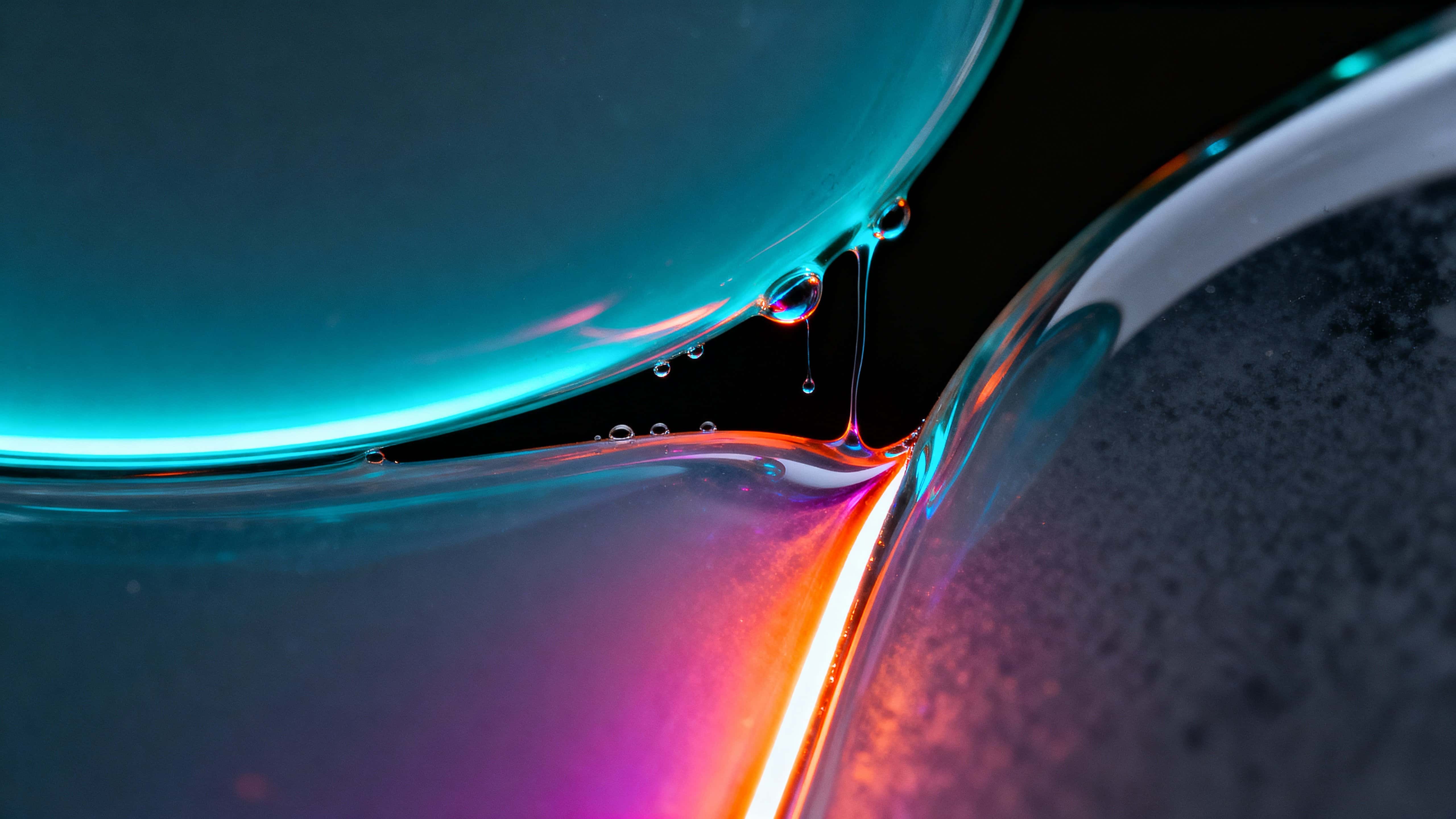 Extreme macro of two liquid-glass slabs parting along a glowing lower-third seam, cyan and magenta-orange filaments and droplets against a deep charcoal-black field.