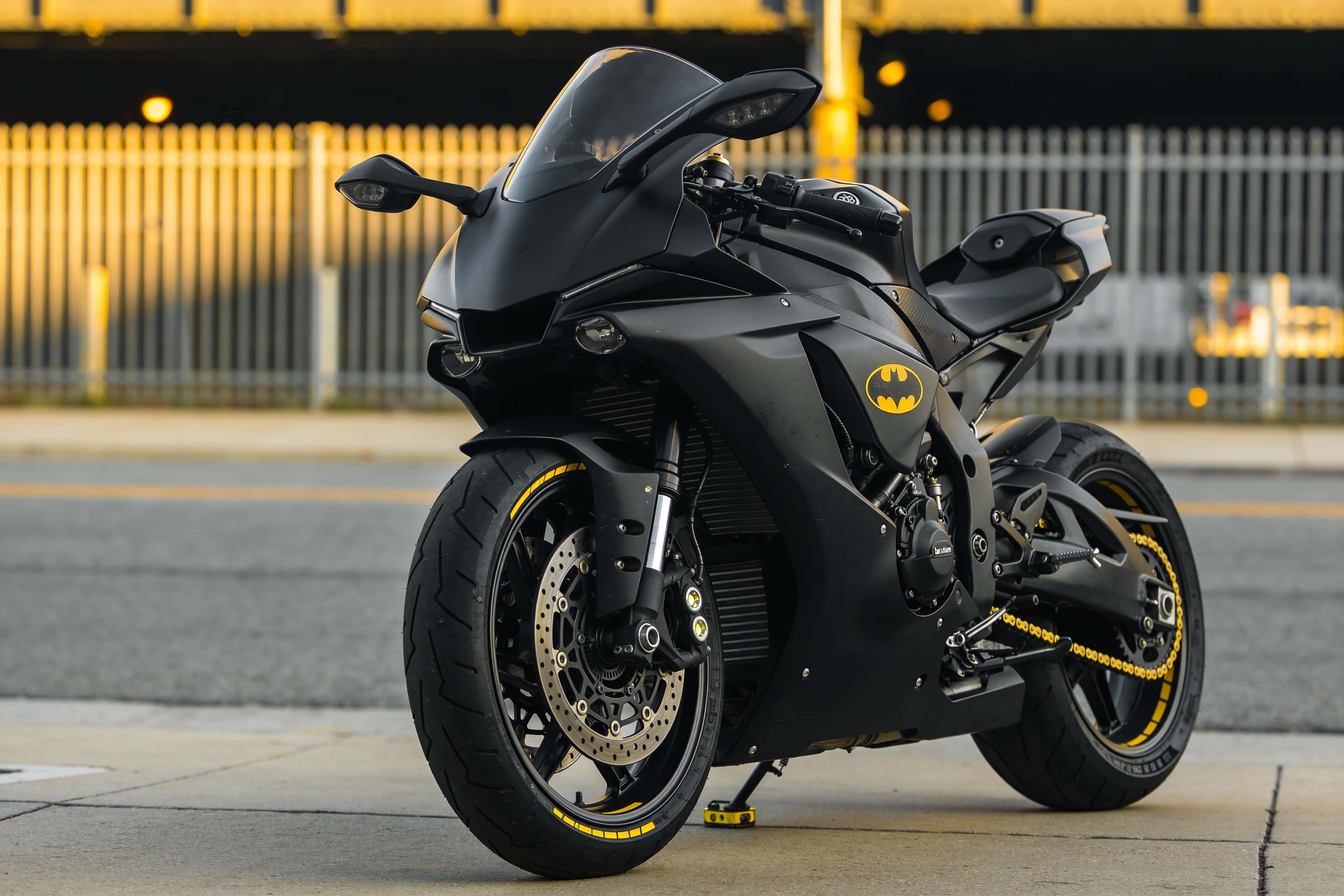 A matte-black sport motorcycle photographed as a low-angle product study that fills the lower two-thirds of a 3:2 poster-cover composition with dramatic rim lighting.