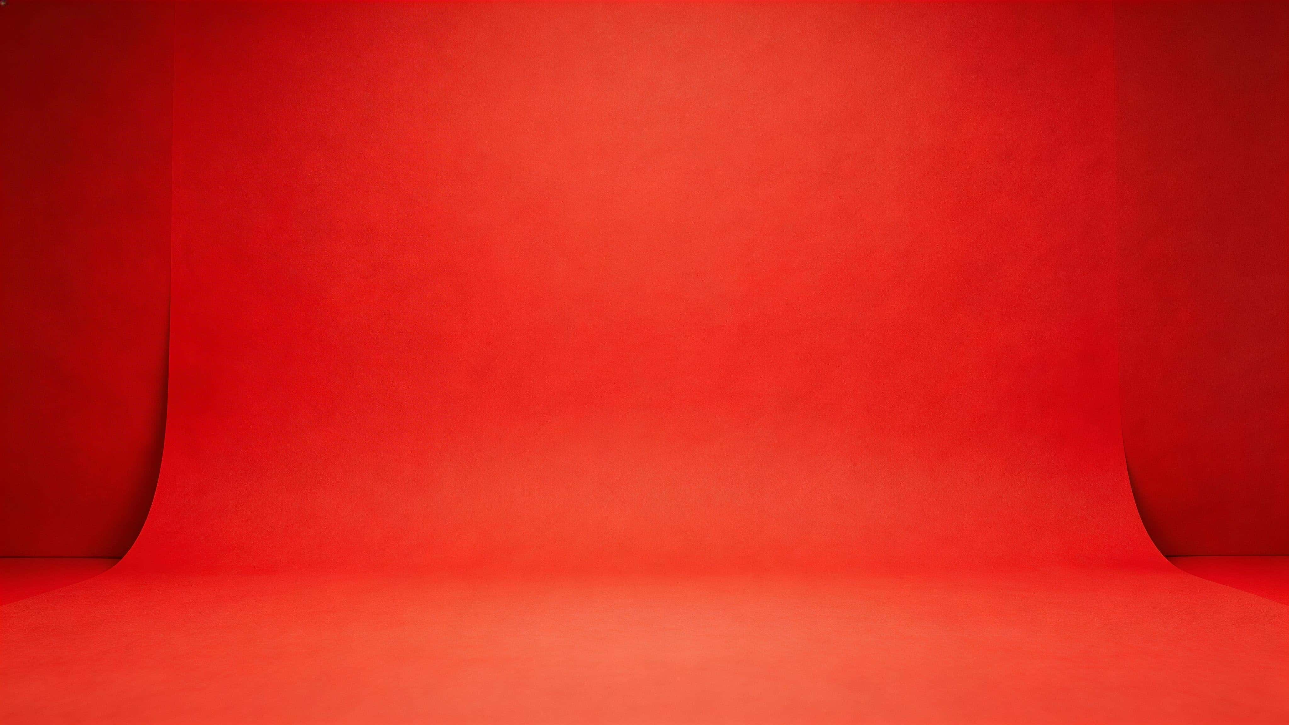 Widescreen 16:9 studio product shot of a matte-red seamless paper backdrop with a smooth sweep, gentle floor-to-wall curve, soft diffusion and subtle falloff.