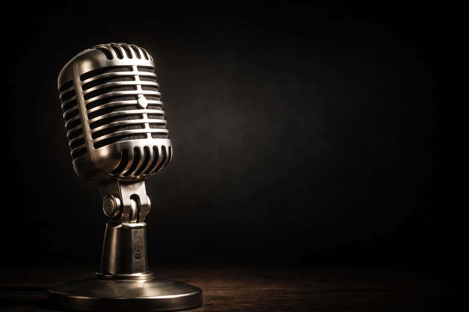 A dust-coated microphone photographed as a moody still-life in product photography, composed for a 3:2 poster-cover with dramatic spotlight and textured shadows.