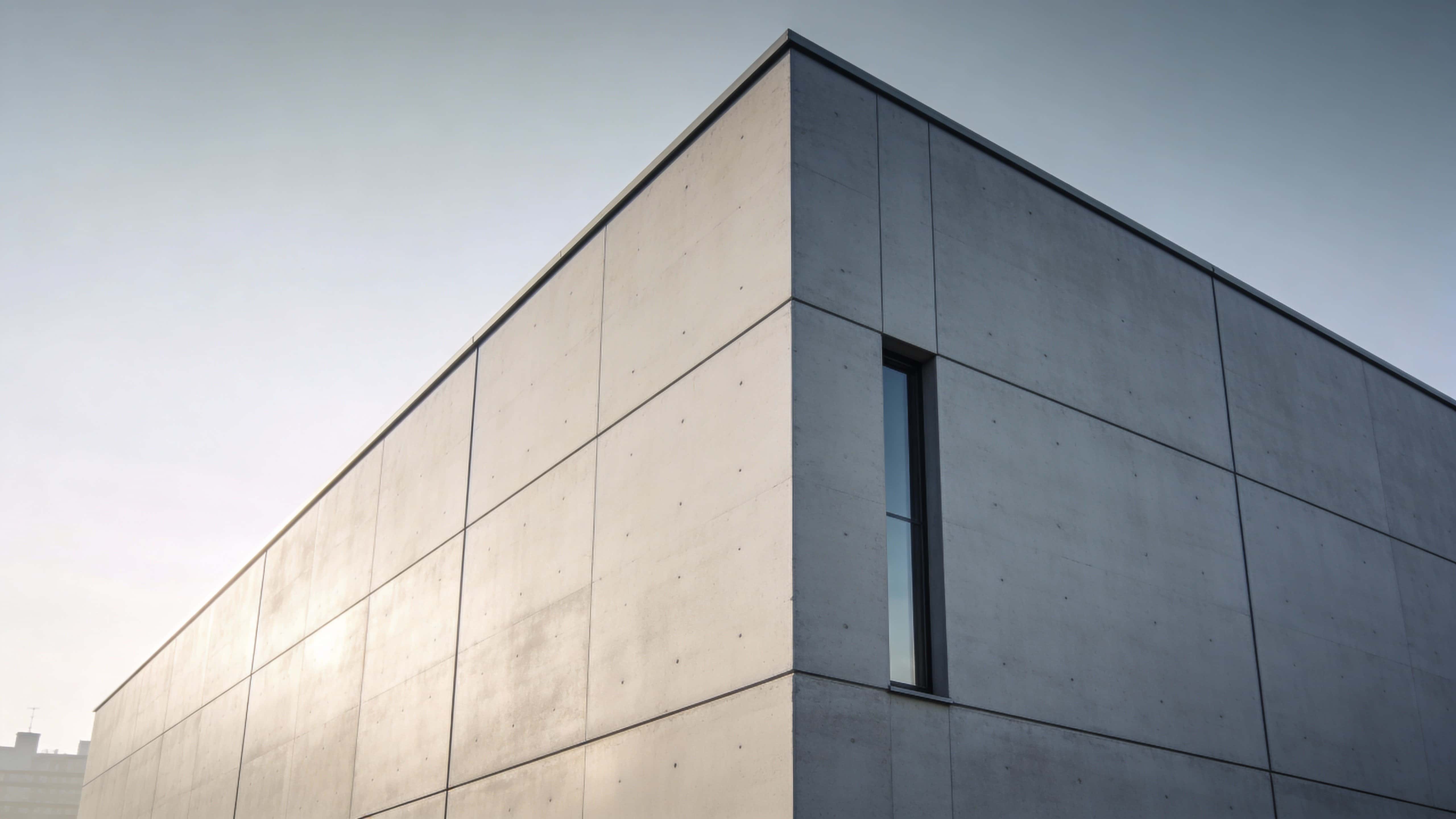 A minimalist modern building facade photographed for a 16:9 poster-cover, emphasizing geometric planes, clean materials, and balanced negative space with calm light.