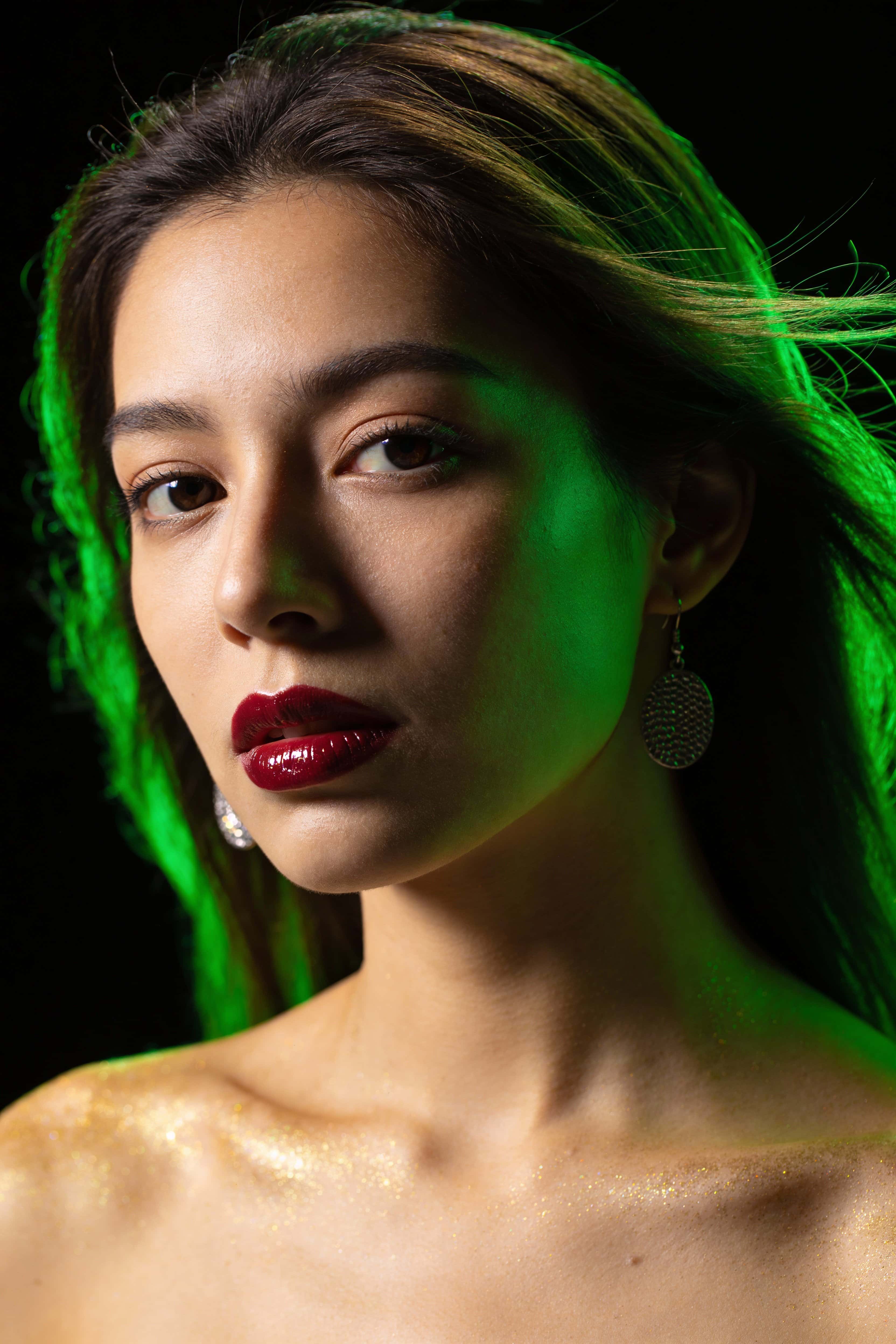 Close 2:3 portrait of a single woman lit by intense green rim light, photographic realism for wallpaper or poster use with faithful composition and crop guidance.