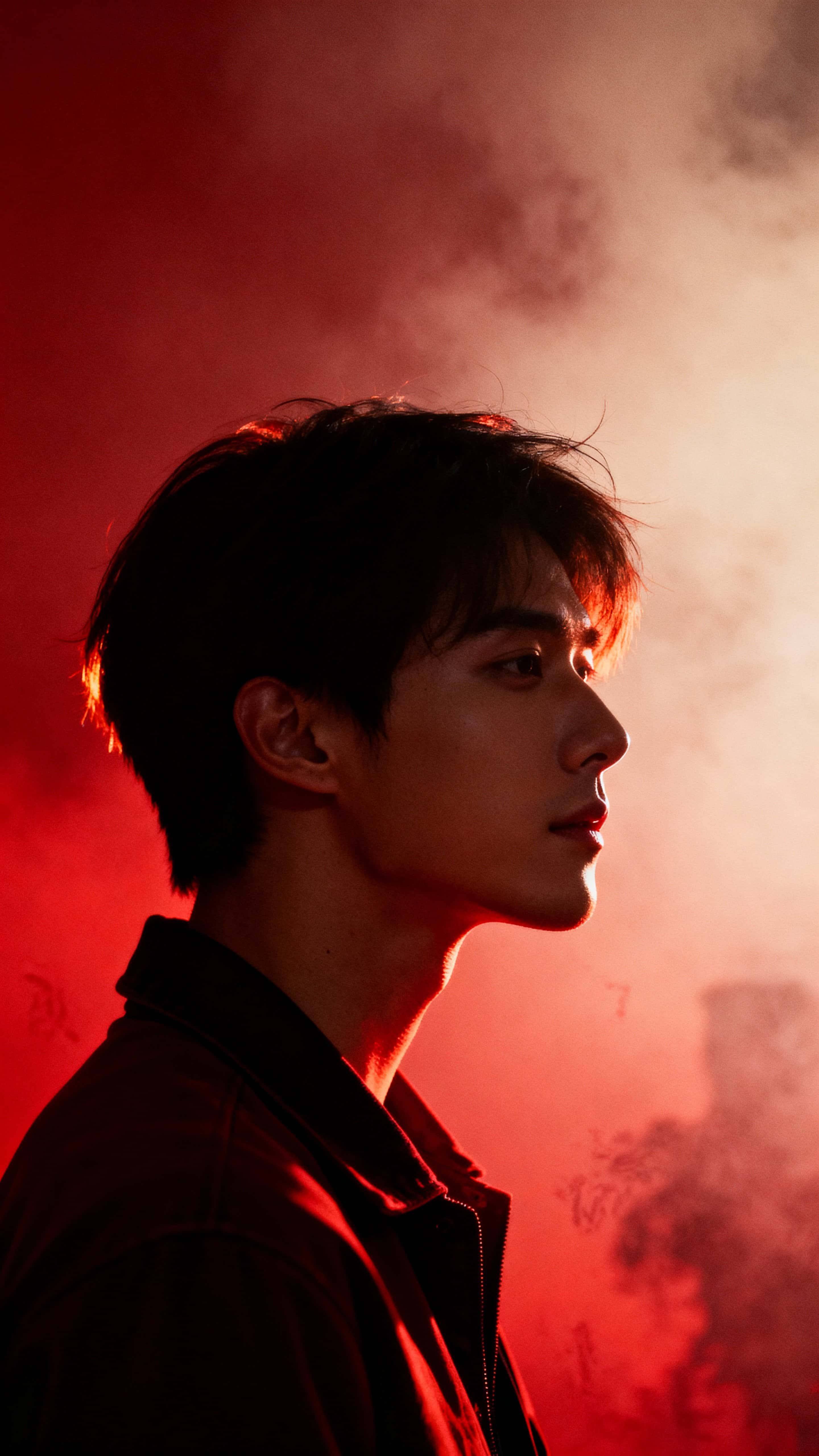 A backlit silhouette of a person framed tall in a 9:16 crop, with a warm red haze and rim-lit hair while the jawline and cheek catch the only clear highlights of the face.