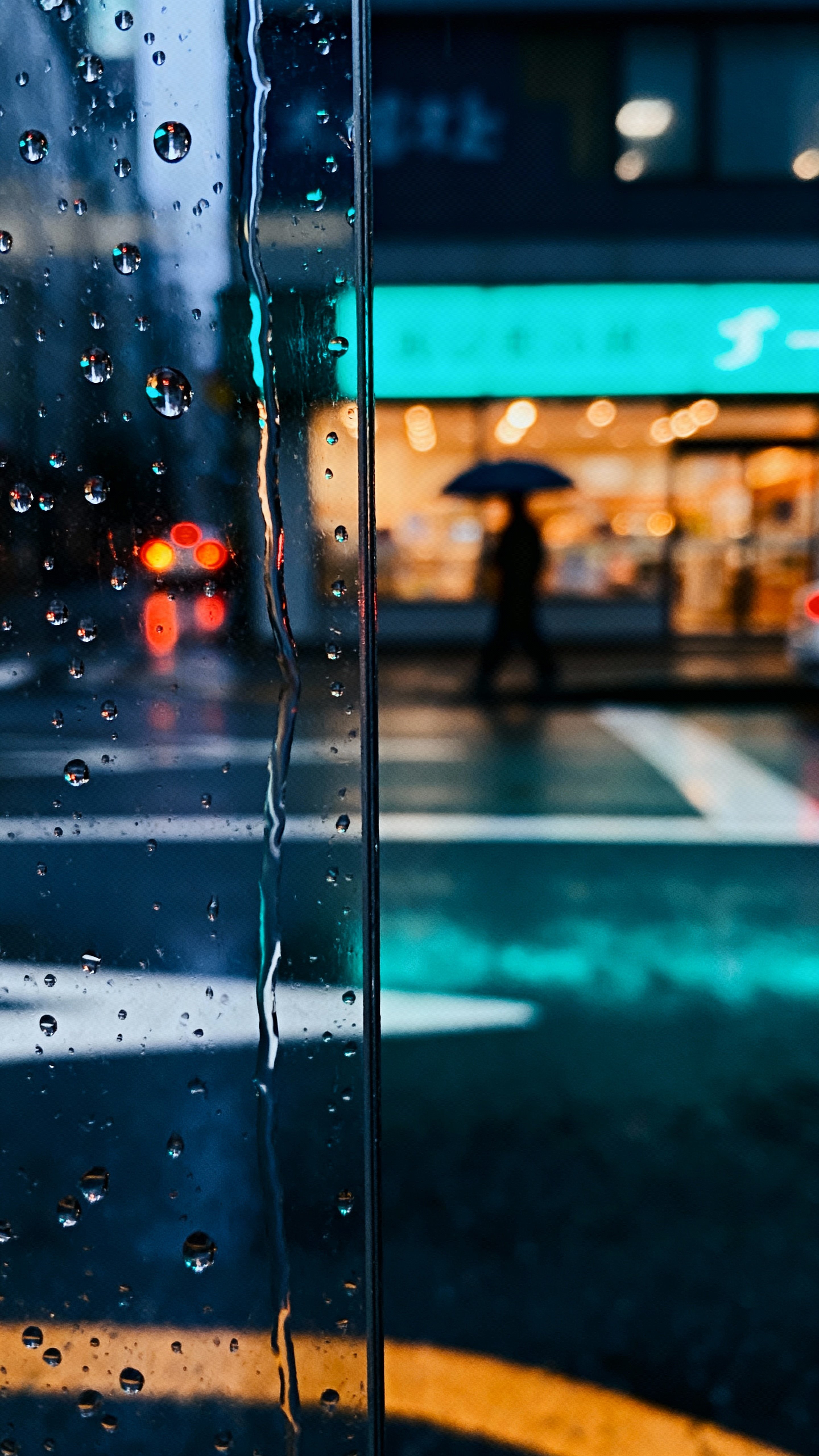 A moody, vertical view of a rainy urban street seen through a glass window with raindrops, soft reflections, and blurred figures framed for a tall 9:16 composition with cinematic light effects.