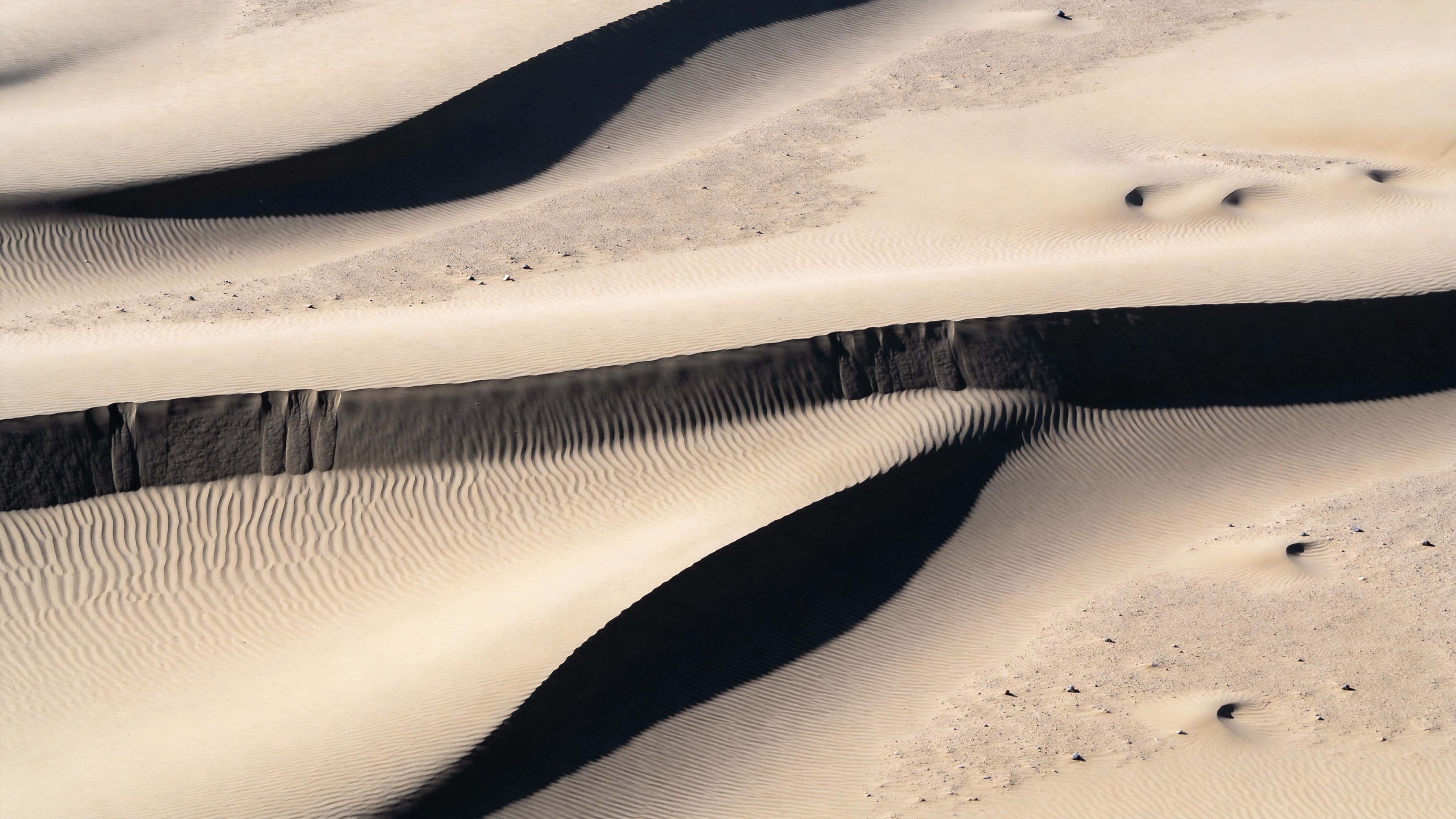 Birds-eye abstract photography of wind-sculpted sand ripples in a 16:9 frame, composed for wallpaper use with calm, minimal mood and precise crop guidance.