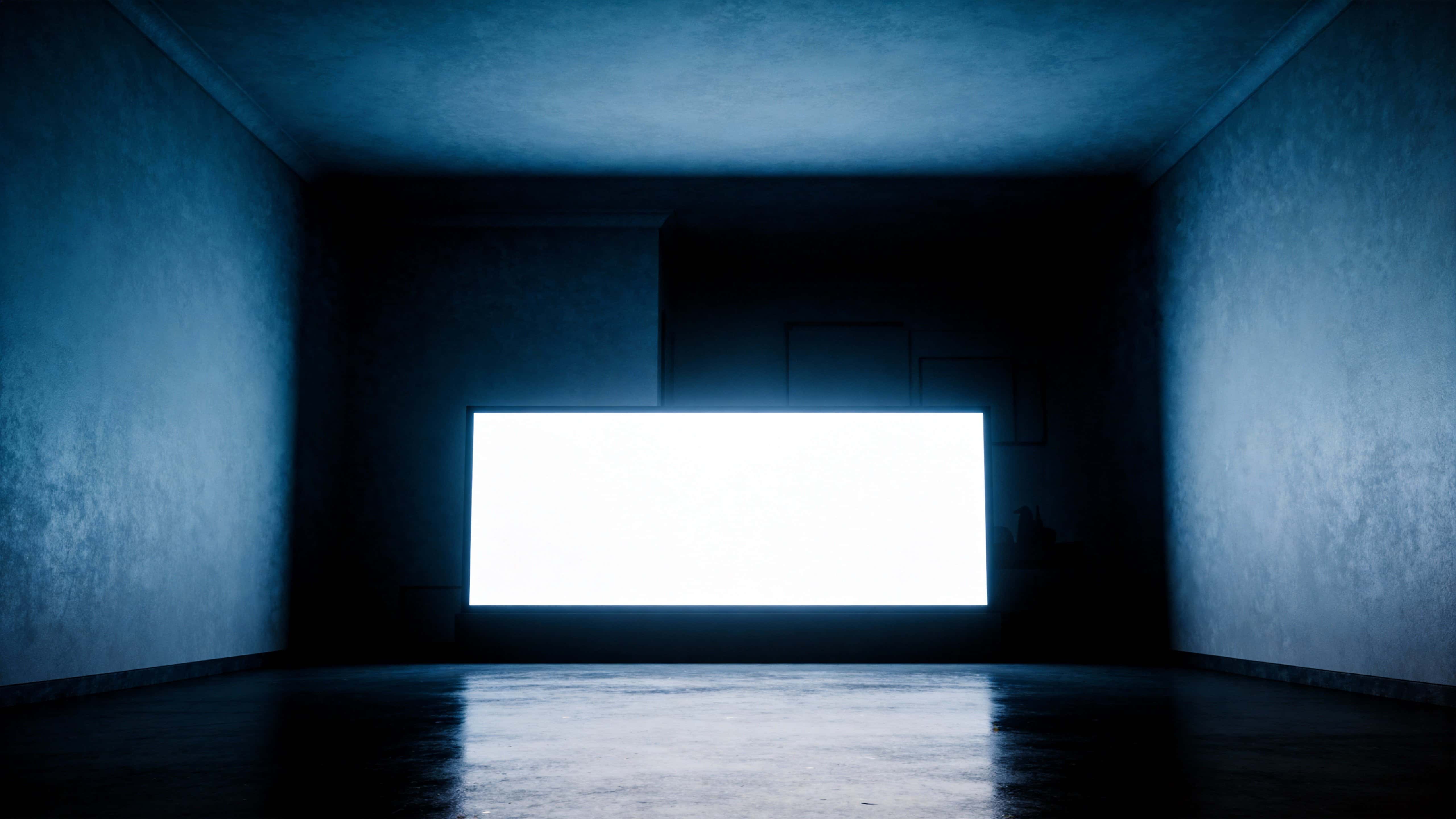 A low-key interior photograph of a dark room with a single illuminated screen as focal point, composed for a 16:9 wallpaper-style image with strong negative space.