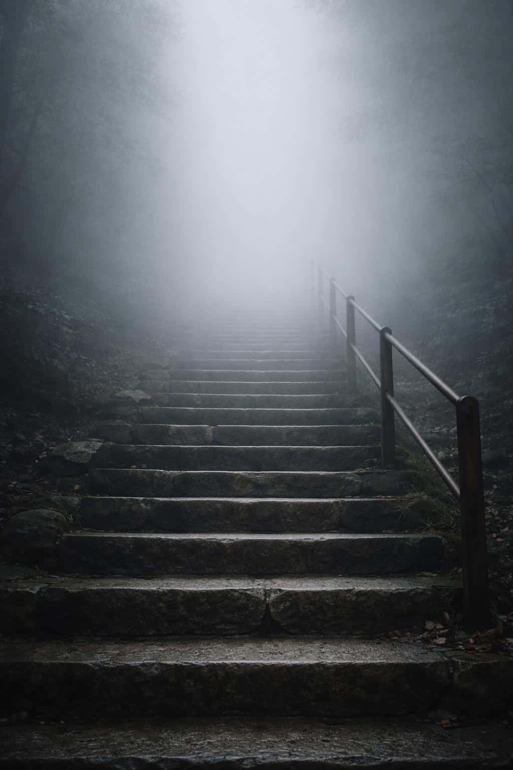 Staircase vanishing into dense fog captured as a vertical 2:3 fine-art composition with strong leading lines, minimalist mood and poster or wallpaper intent.