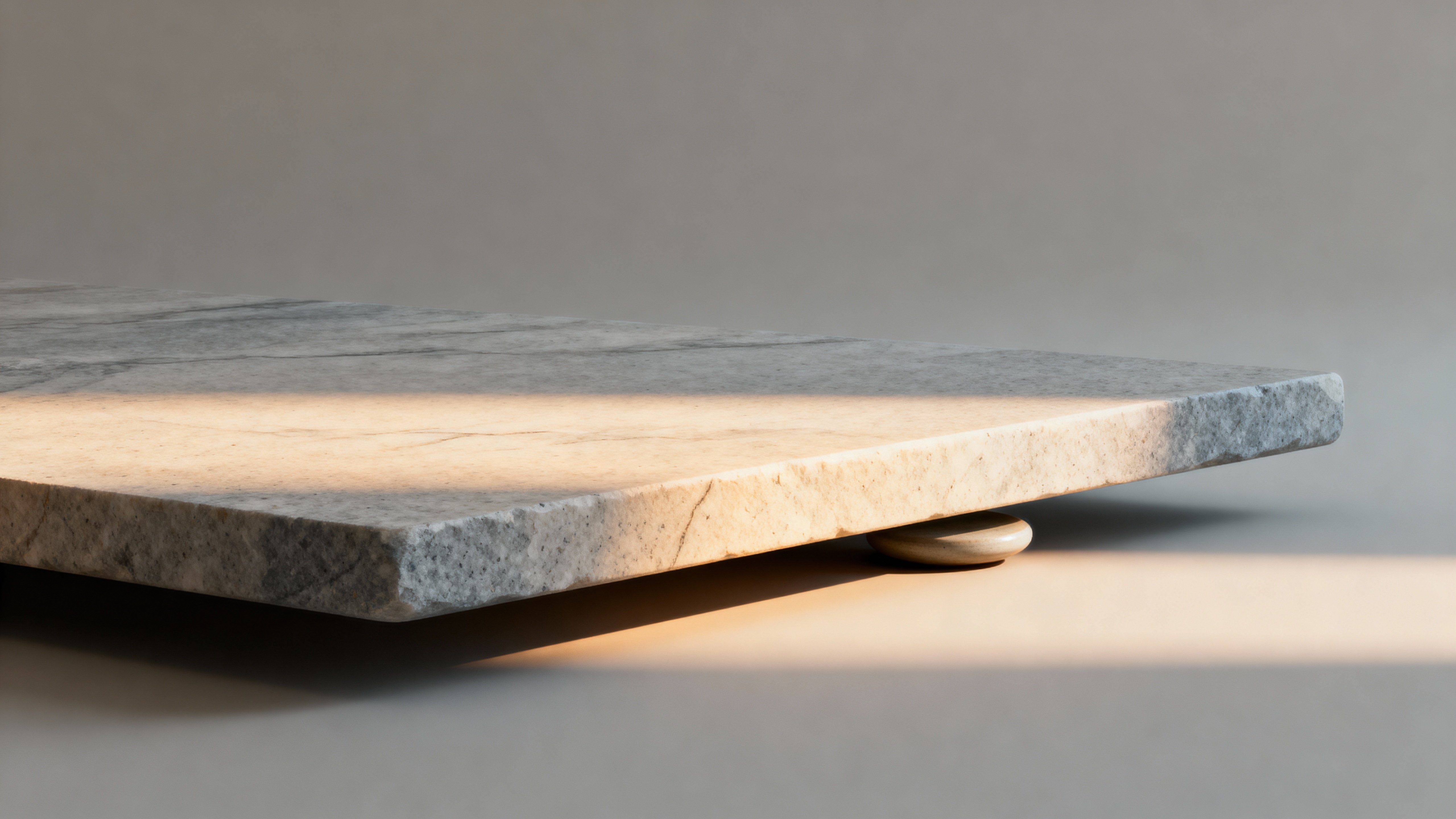 A minimal, close-cropped stone surface rendered as a smooth gradient across a 16:9 frame, emphasizing tactile grain and subtle tonal shifts for calm, modern backgrounds and material studies.