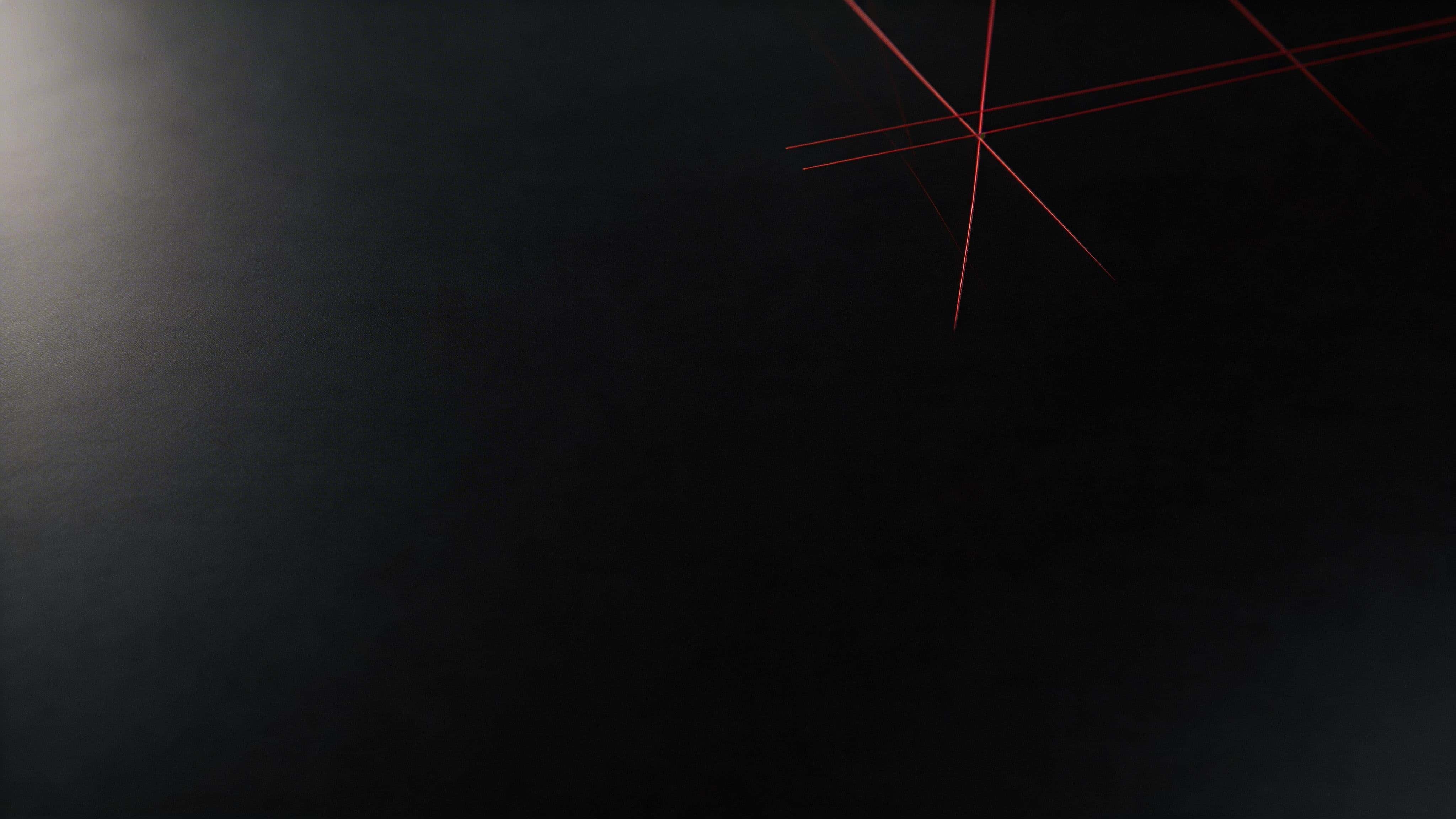 16:9 widescreen wallpaper of a sparse, off-center crimson tech grid etched into matte glass, fading into deep near-black negative space for icons.