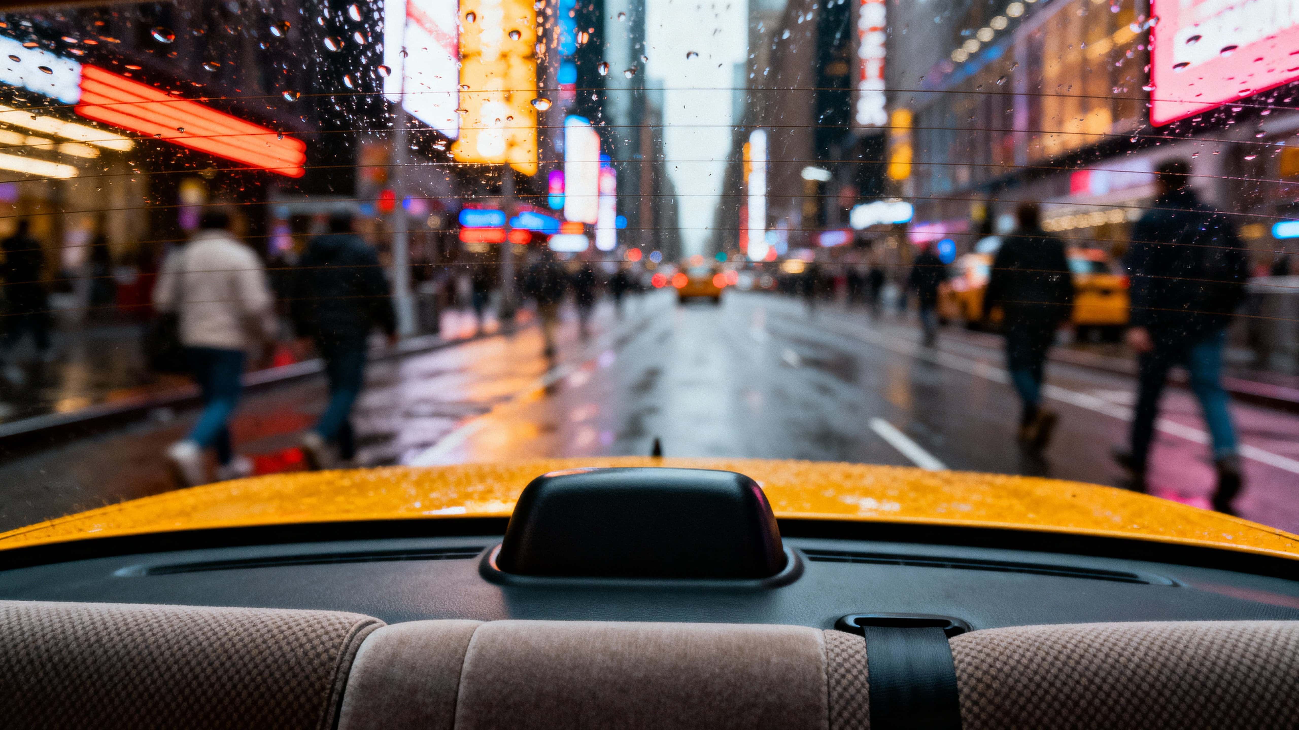 A rainy view of Times Square seen from inside a yellow taxi, raindrops beading on the window, glowing billboard reflections and blurred pedestrians conveying cinematic isolation amid chaos.