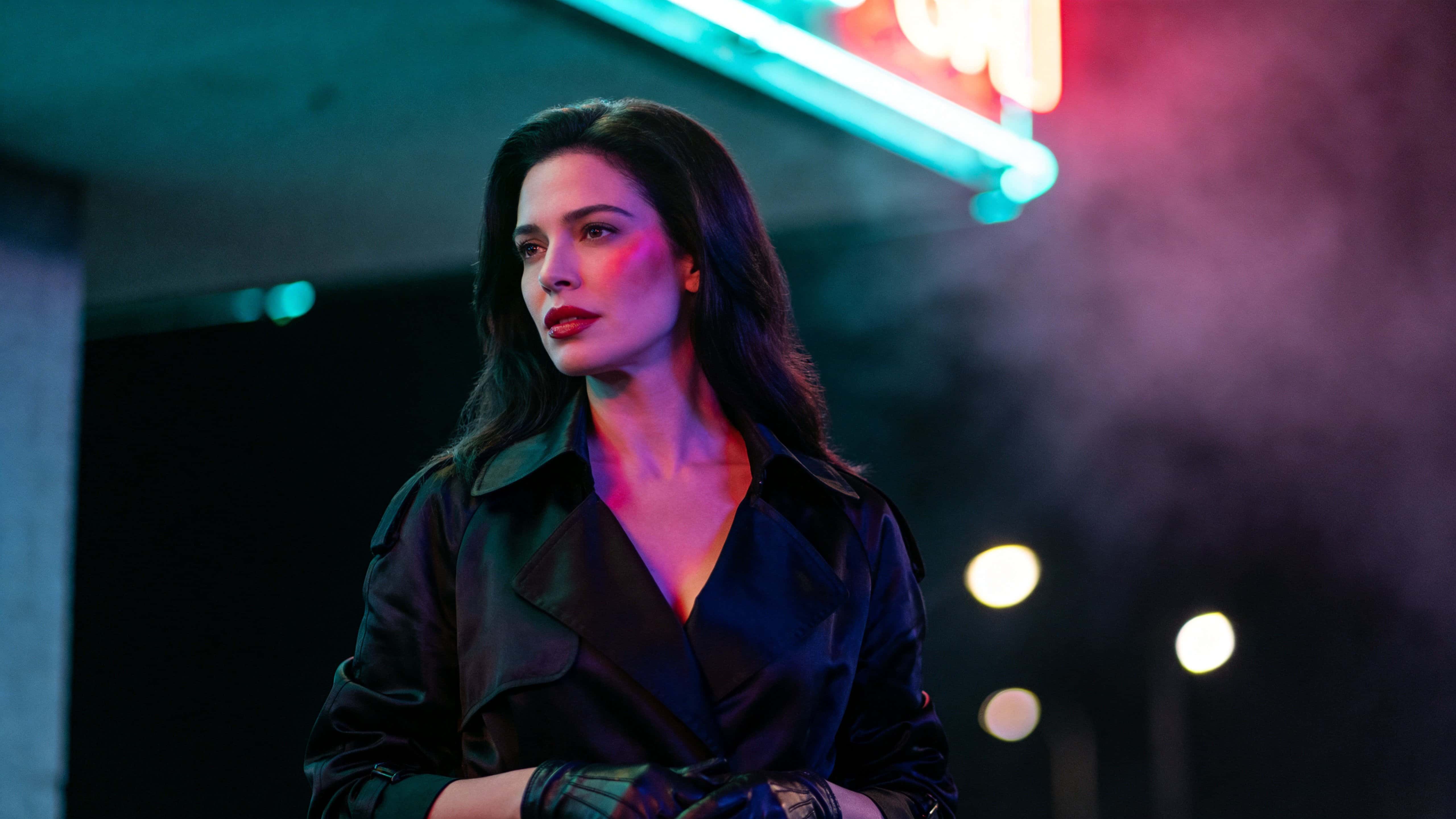 A widescreen 16:9 cinematic street scene of a woman in her early 30s standing on the left third under teal and electric magenta neon, rim-lit with soft mist and bokeh, high-contrast and crisp.