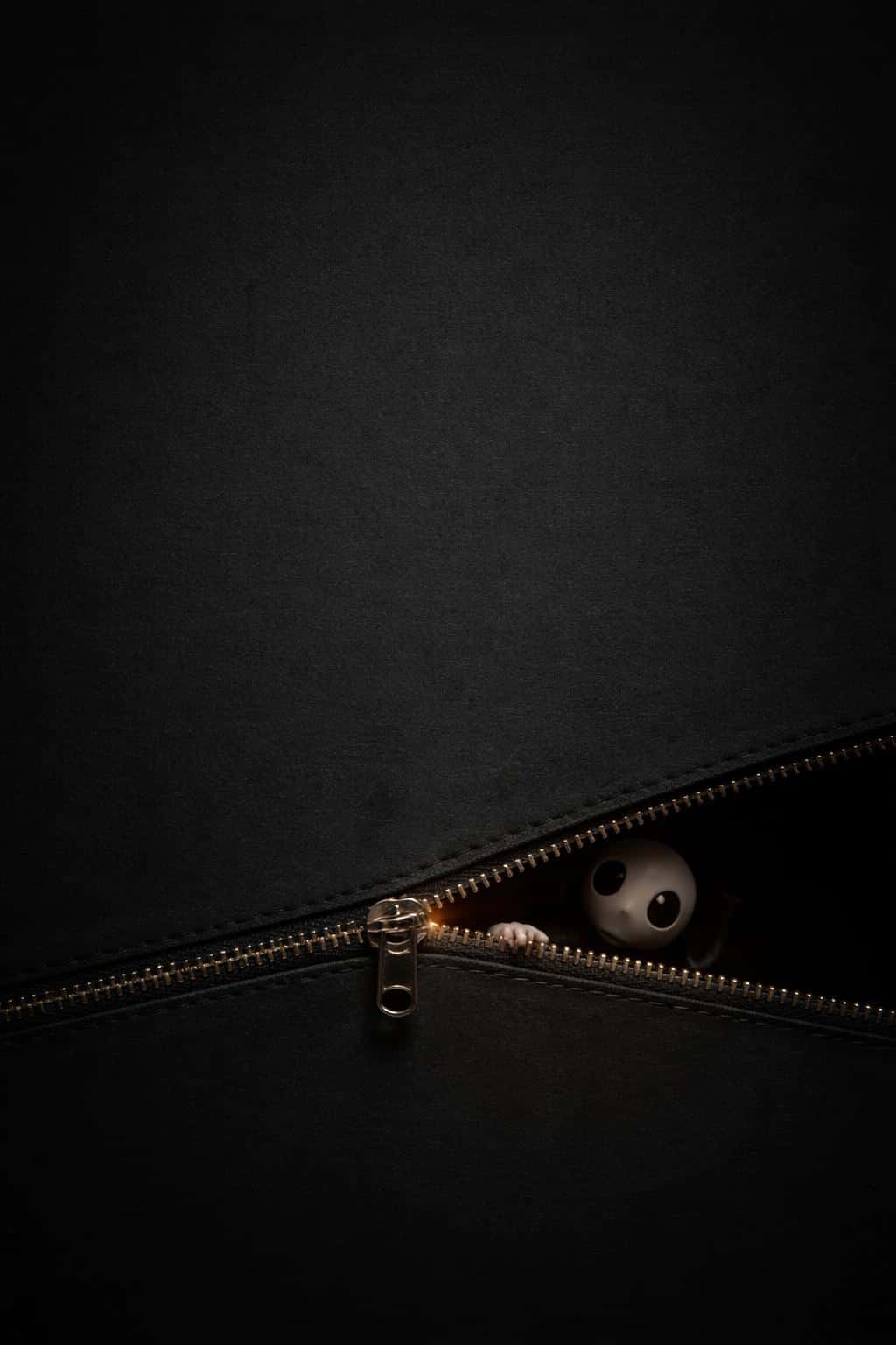 Minimal 2:3 composition with a deep charcoal grained background and a narrow lower-third zipper revealing warm amber light and a mask-like sprite.